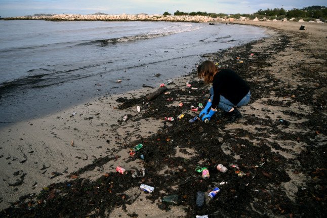 Une femme ramasse des déchets sur une plage après de fortes pluies et suite à une grève des éboueurs à Marseille.