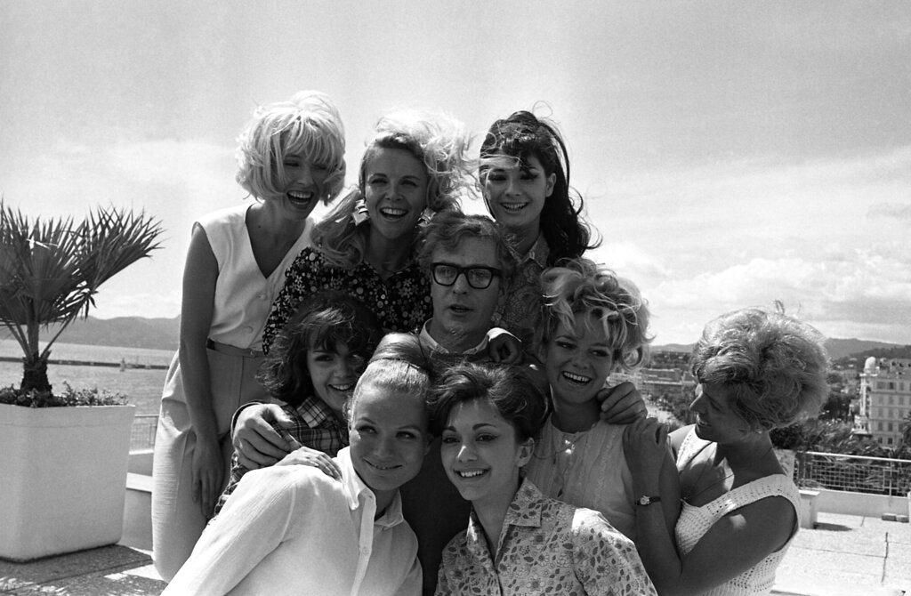L'acteur britannique Michael Caine pose avec un groupe de filles après sa conférence de presse sur un toit à Cannes le 9 mai 1966. Il faisait la promotion de son film Alfie.