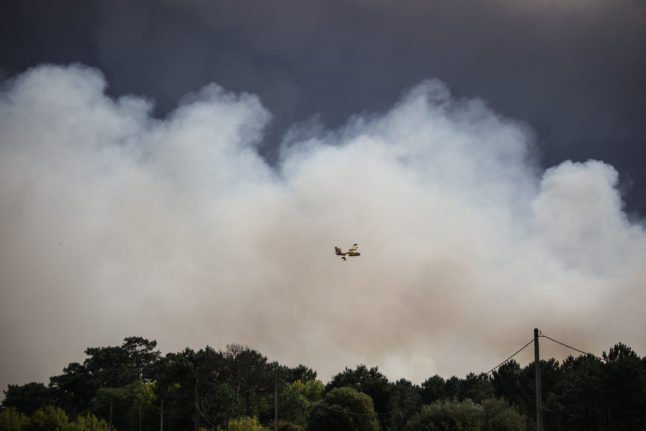 Un avion vole près de la fumée d'un feu de forêt à Cazaux, en France.